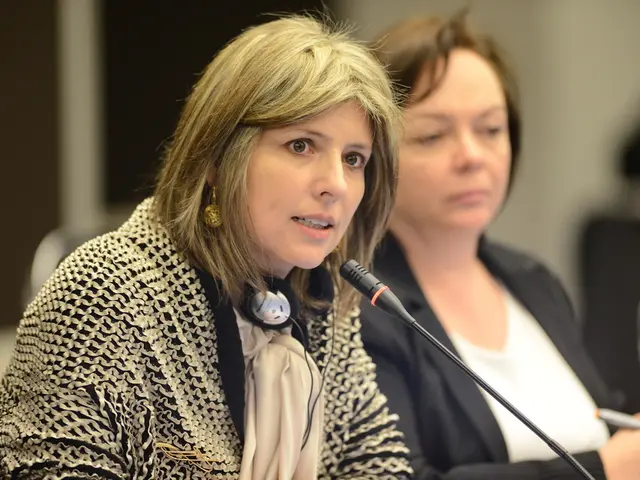 In the picture we can see two women are sitting in the chairs near the desk and one woman is...