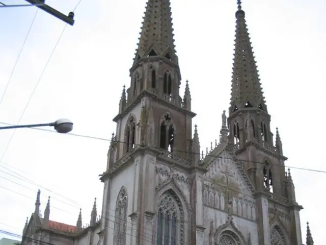 In the center of the image there is a church. At the bottom of the image there is road on which...