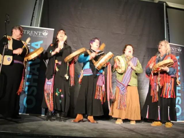 In this picture there is a group of women wearing colorful dresses singing and holding the drums in...
